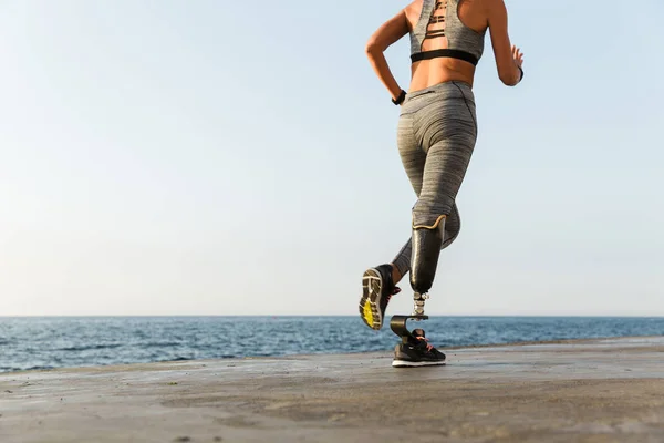 裁剪后的年轻惊人的残疾体育妇女运行在海滩上的视线 — 图库照片
