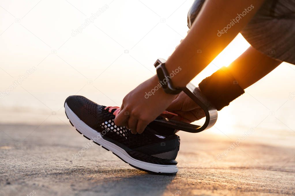 Close up of disabled athlete woman with prosthetic leg tying shoelace outdoor