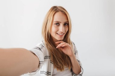 Beyaz arka plan üzerinde izole uzanmış kollu selfie alarak genç ve güzel casual kız
