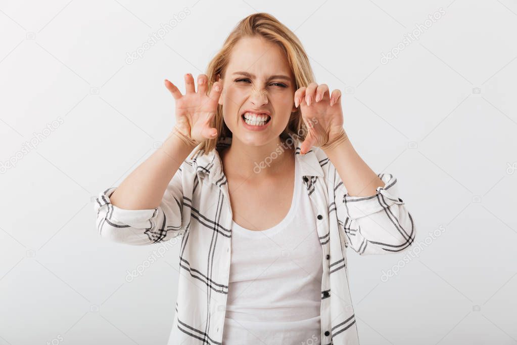 Portrait of an angry young casual girl making cat claws gesture isolated over white background