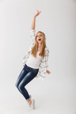 Tam uzunlukta kulaklık ile müzik dinlemek ve beyaz arka plan üzerinde izole dans neşeli genç casual kız