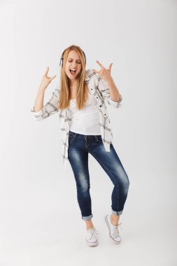 Tam uzunlukta kulaklık ile müzik dinlemek ve boynuzları beyaz arka plan üzerinde izole jest kadar gösterilen serin genç casual kız