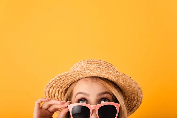 关闭半脸肖像的一个漂亮的年轻金发女郎在夏季帽子和太阳镜寻找孤立的黄色背景 — 图库照片