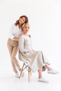 Genç kadının beyaz arka plan üzerinde izole annesiyle poz resim. Görünümlü kamera.