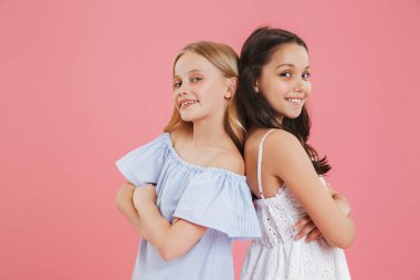 Esmer ve sarışın bayan arkadaşlar gülümseyen ve kamera duran kollarını arkaya bakarak etek giydiğini resim closeup izole pembe arka plan üzerinde çarpı işareti