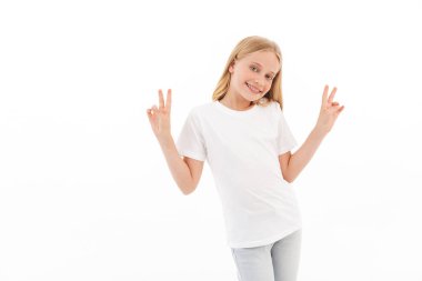 Beyaz duvar arka plan üzerinde izole oldukça sevimli kız ayakta görüntüsü. Kamera olun barış hareketi arıyorsunuz.