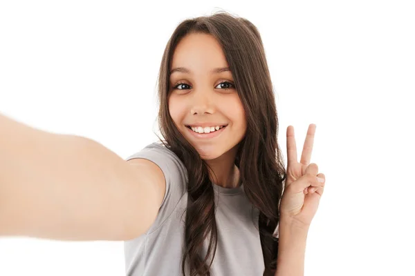 白い壁の背景の上に分離立っているかわいい女の子の画像を作る平和のジェスチャーを示すカメラを探して Selfie — ストック写真