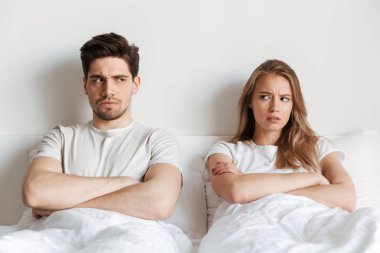 Genç memnun negatif rahatsız sevgi dolu çift yatak kavgası içinde yatıyor.