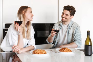 Genç mutlu sevgi dolu çift mutfakta spagetti yemek bir yemek içme şarap var.