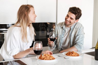 Genç mutlu sevgi dolu çift mutfakta spagetti yemek bir yemek içme şarap var.