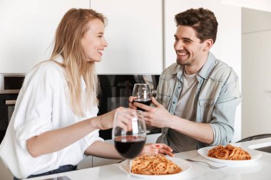Genç mutlu sevgi dolu çift mutfakta spagetti yemek bir yemek içme şarap var.