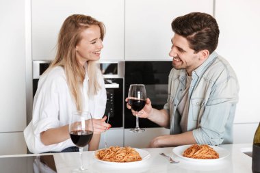 Genç mutlu sevgi dolu çift mutfakta spagetti yemek bir yemek içme şarap var.