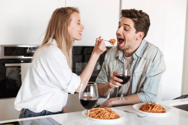 Genç mutlu sevgi dolu çift mutfakta spagetti yemek bir yemek içme şarap var.