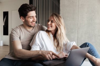 Dizüstü bilgisayar kullanan iç kanepe üzerinde ev genç Sevimli mutlu sevgi dolu çiftin fotoğraf.