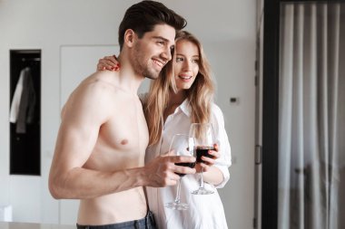 Genç Sevimli neşeli sevgi dolu çift evde kapalı şarap içme.