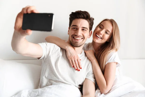Image Young Cheerful Loving Couple Lies Bed Take Selfie Smartphone — Stock Photo, Image