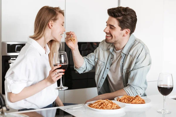Genç mutlu sevgi dolu çift mutfakta spagetti yemek bir yemek içme şarap var.