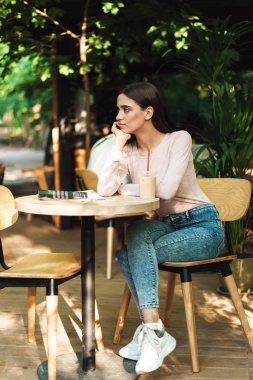 Bir kafede otururken açık havada bir smoothies ile dergi okuma sıkılmış genç kız