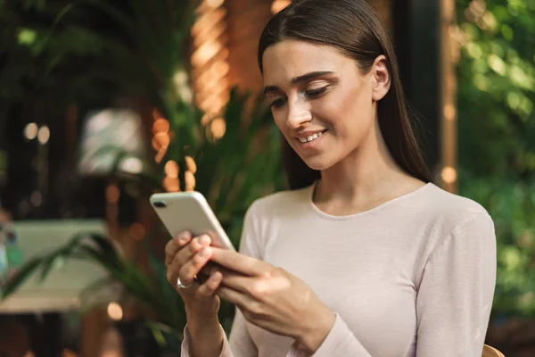 Mosolygó Fiatal Lány Nézett Mobil Telefon Miközben Egy Kávézó Szabadban — Stock Fotó