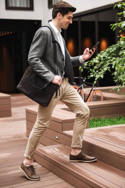 Tam uzunlukta merdivenlerinde açık havada yürüyüş gülümseyen genç işadamı