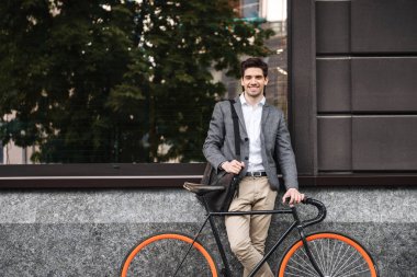 Açık havada bir bisiklet ile ayakta iken bir duvara yaslanmış dostu genç işadamı