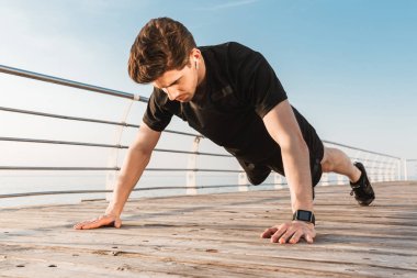 Yakışıklı genç sporcunun fotoğrafı spor egzersizleri açık havada beach kulaklık ile müzik dinleme yapmak.