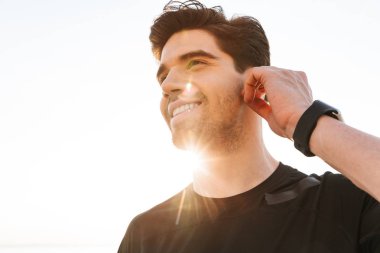 Genç yakışıklı sporcu beach müzik dinleme üzerinde açık havada fotoğraf.