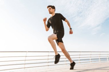 Açık havada beach kulaklık ile müzik dinleme üzerinde çalışan yakışıklı genç sporcu görüntüsünü.