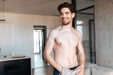 Gülümseyen genç adam onun t-shirt duran bir oturma odası holding