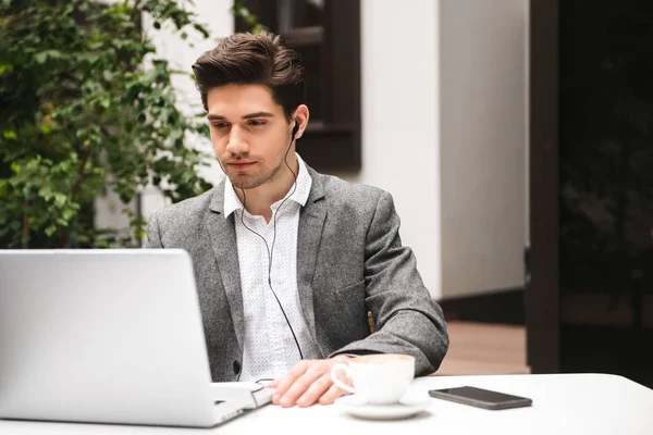 Retrato Jovem Empresário Sério Fones Ouvido Olhando Para Computador Portátil — Fotografia de Stock