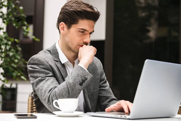 Retrato Joven Hombre Negocios Serio Usando Ordenador Portátil Mientras Bebe — Foto de Stock