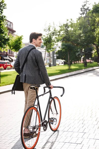 街で自転車と一緒に歩く若いビジネスマンの背面図 — ストック写真