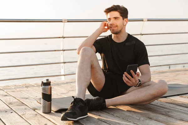 Foto Belo Jovem Desportista Sentado Livre Praia Ouvindo Música Com — Fotografia de Stock