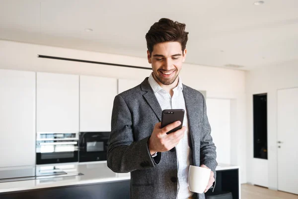 Hombre Joven Feliz Traje Mirando Teléfono Móvil Mientras Bebe Café — Foto de Stock