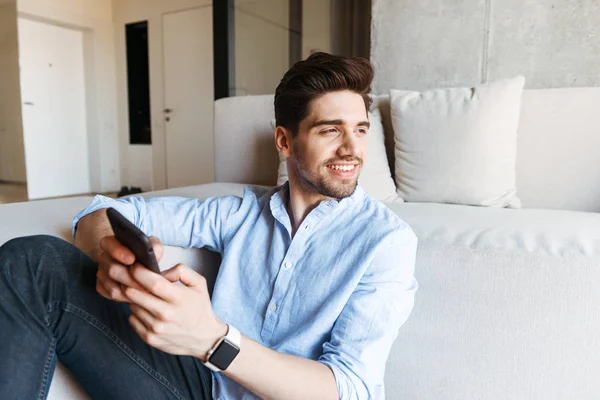 Joven Feliz Usando Teléfono Móvil Mientras Está Sentado Sofá Piso — Foto de Stock