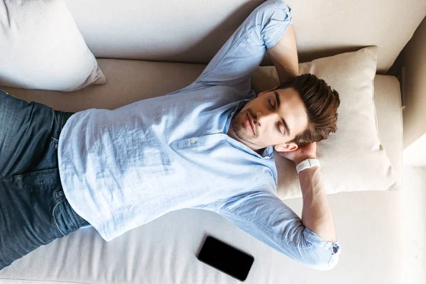 Ovanifrån Ung Man Som Sover Soffan Hemma Med Mobiltelefon — Stockfoto