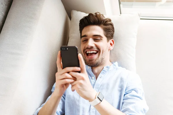 Pohled Shora Veselý Mladý Muž Používá Mobilní Telefon Když Leží — Stock fotografie