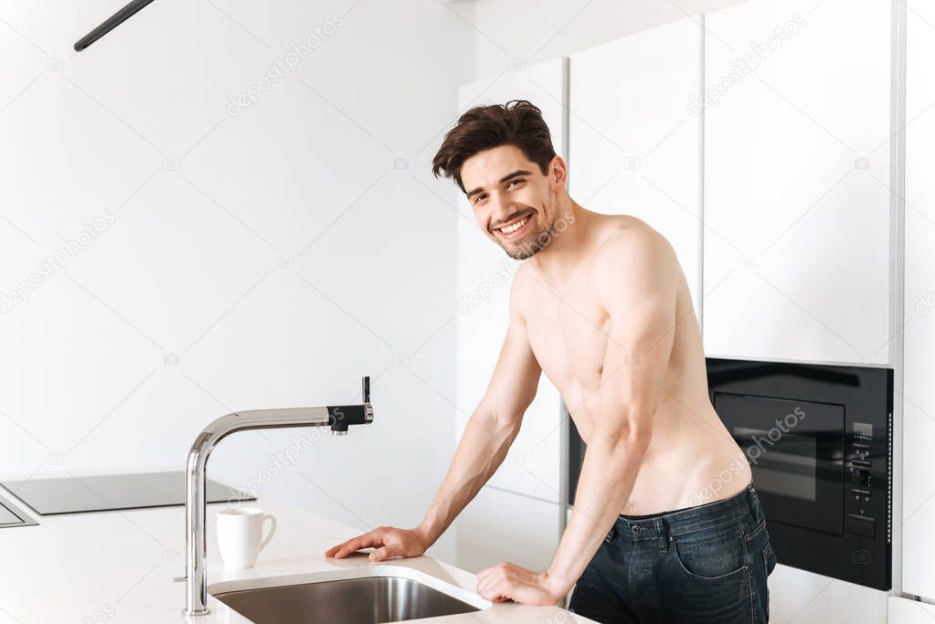 Smiling shirtless man standing at the kitchen
