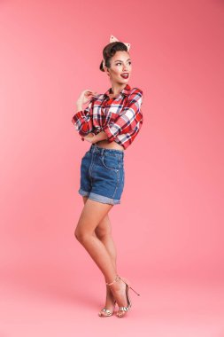 Pembe arka plan üzerinde kafa bandı uzağa bakarak bir güzel güzel esmer pin-up kadın portresi tam uzunlukta izole