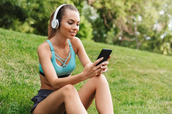 Smiling Young Sportswoman Dressed Sportswear Headphones Resting While Sitting Grass — Stock Photo, Image