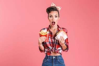 Şok holding Fransız kızartması ve burger pembe arka plan duvardan izole pin-up kadının genç görüntü.