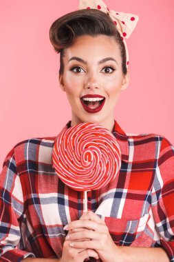 Pin-up üzerinde pembe bir arka plan duvar candy lolipop tutan izole kadın resmi heyecanlı şaşırttı.