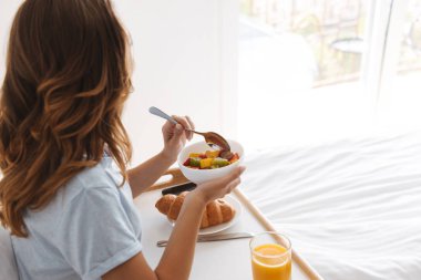 Genç kadın yatakta bir tepsi üzerinde sağlıklı kahvaltı yan görünüm