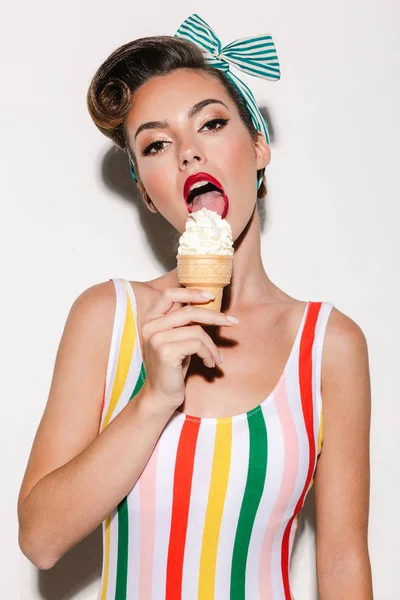 Image of beautiful pin up woman isolated over white wall background eating ice cream.