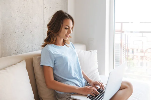 Mujer Joven Feliz Sentado Sofá Casa Con Ordenador Portátil —  Fotos de Stock