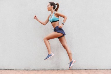 Kendine güvenen genç sporcumuz yan görünüm açık havada duvara ısınma spor giyim giyinmiş