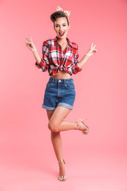 Barış hareketi gösterilen pembe arka plan duvardan izole genç ve güzel pin-up kadın görüntüsünü.