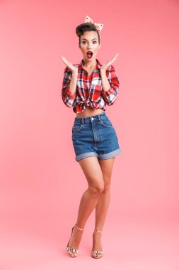 Görüntü oldukça şok genç pin-up kadın kamera seyir pembe arka plan duvardan izole.