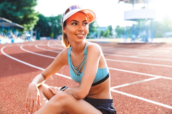 Glimlachend Jonge Sportsgirl Gekleed Sportkleding Cap Zit Een Stadium Zoek — Stockfoto