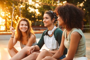 Açık havada birbirleri ile bahseden genç mutlu üç arkadaş kadın görüntüsünü.